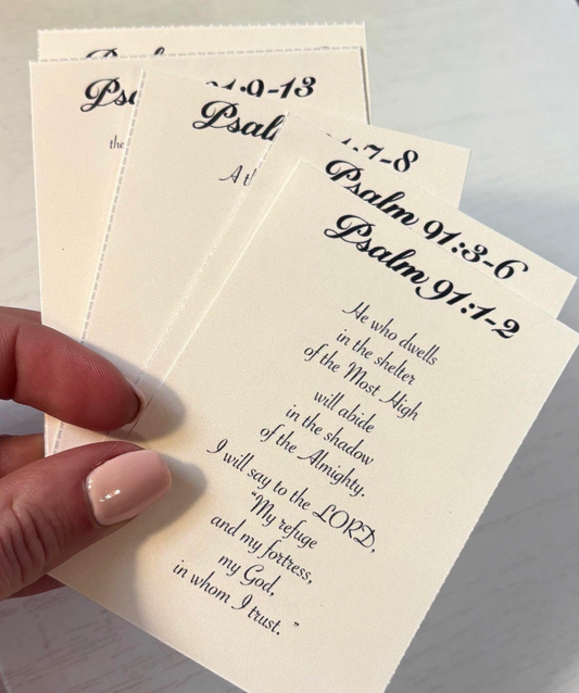 Hand holding a sheet of paper with printed text, likely from a religious book or prayer guide.