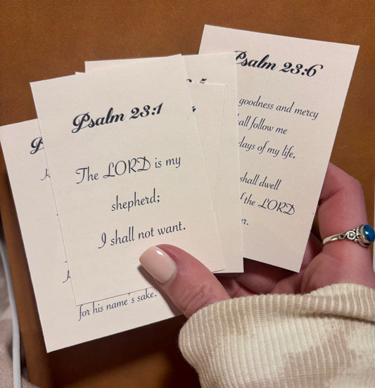 Hand holding small cards with Bible verses, specifically Psalm 23:1 and Psalm 23:6.