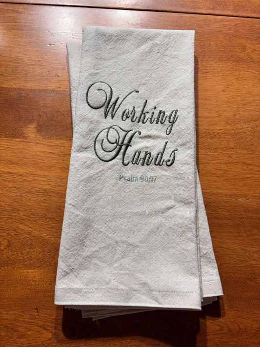 Folded towel with 'Working Hands' text on a wooden surface