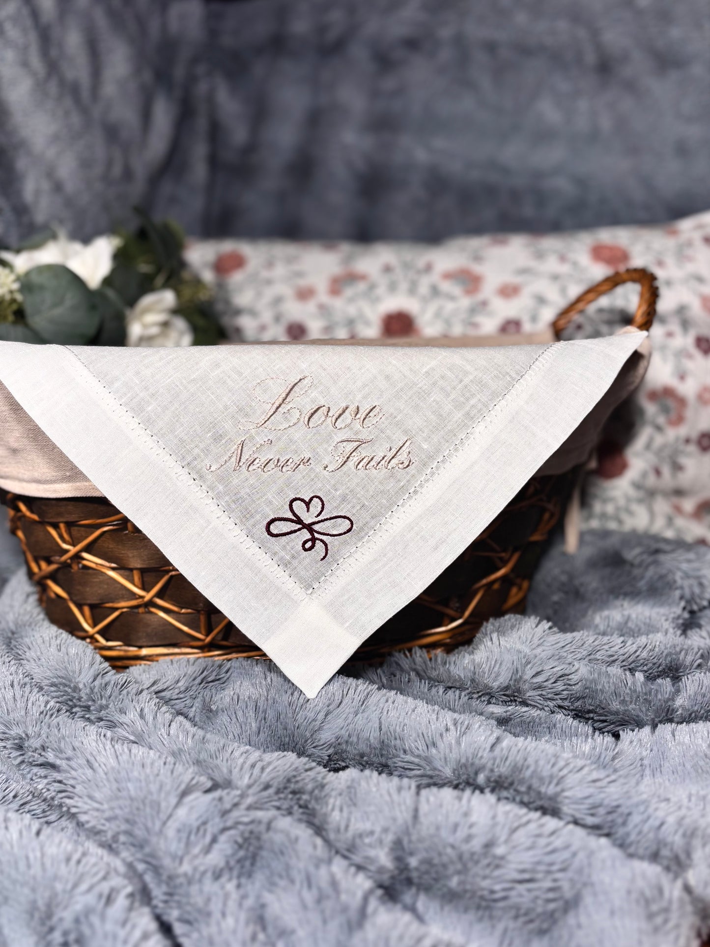 linen handkerchief with 'Love Never Fails' text on a textured surface