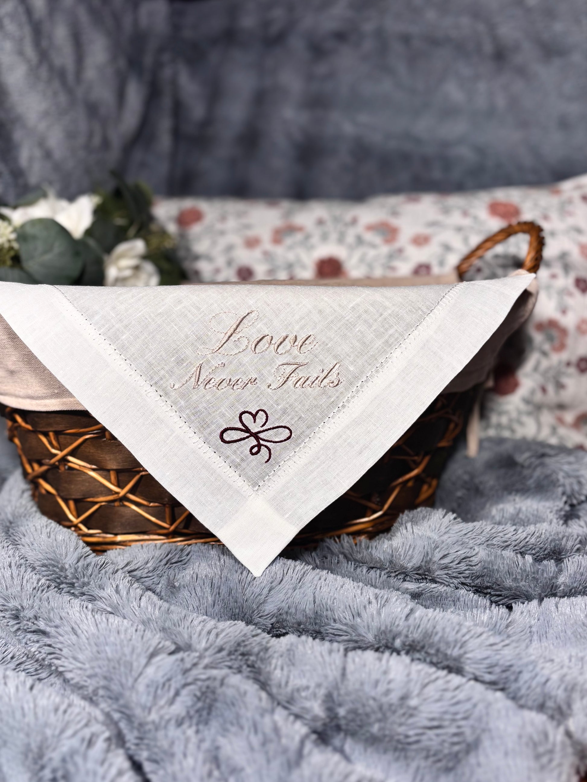 linen handkerchief with 'Love Never Fails' text on a textured surface