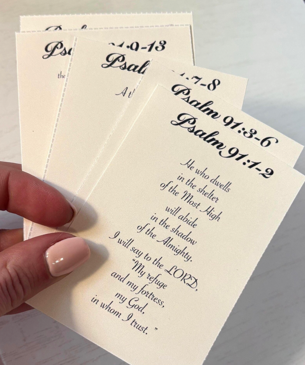 Hand holding a sheet of paper with printed text, likely from a religious book or prayer guide.